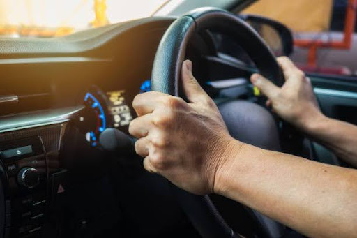 Close-up of a driver gripping the steering wheel with both hands inside a car, dashboard illuminated. Stay road-ready with Dirt Legal’s hassle-free registration services.