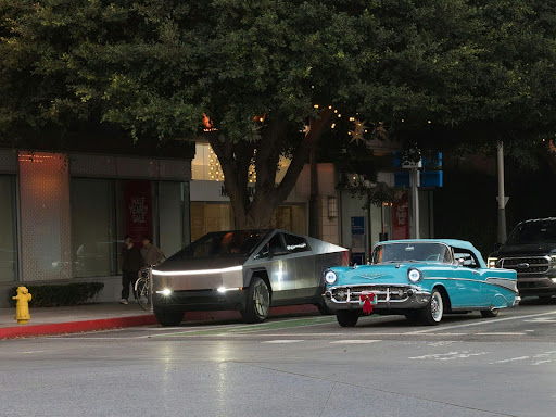 A Tesla Cybertruck and a classic blue Chevrolet parked side by side on a city street—Dirt Legal makes registering any vehicle hassle-free, no matter the era.