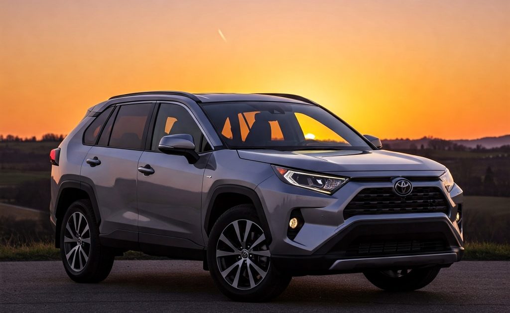 The image features a silver Toyota RAV4 parked outdoors during sunset.