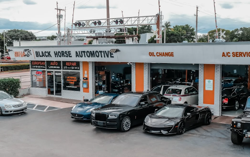 The image shows a luxury auto repair shop named "Black Horse Automotive," with several high-end cars, including a Rolls-Royce, Maserati, and Acura NSX, parked in front.