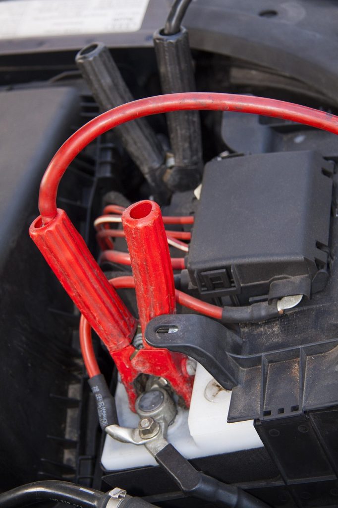 This is a close-up of a car battery with jumper cables attached to jump-start the vehicle.