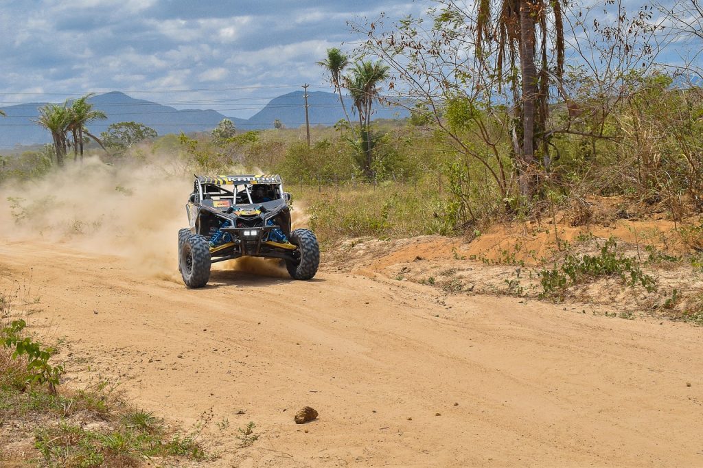 side-by-side off-road utility vehicle (UTV) speeding down a dusty dirt trail.