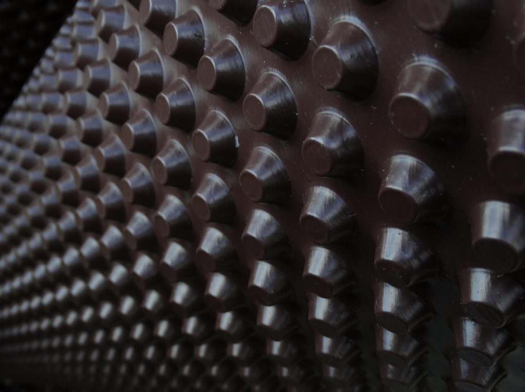 textured underside of a car mat or vehicle floor liner—specifically the kind designed to grip the vehicle floor and prevent slipping.