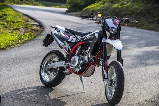 This is a supermoto motorcycle, built for both street and off-road agility, featuring street tires, high suspension, and a minimalist, aggressive design.