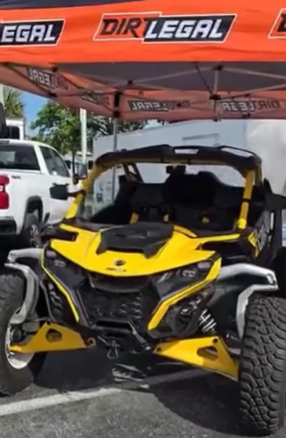 A bright yellow off-road UTV is showcased under a Dirt Legal-branded canopy, highlighting the company’s expertise in making extreme vehicles street-legal.