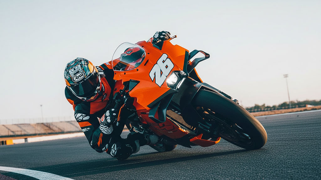 Rider leaning hard into a turn on an orange 2026 KTM 990 RC R sportbike on a race track.